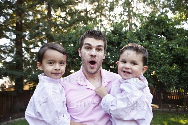 Caucasian father holding sons outdoors