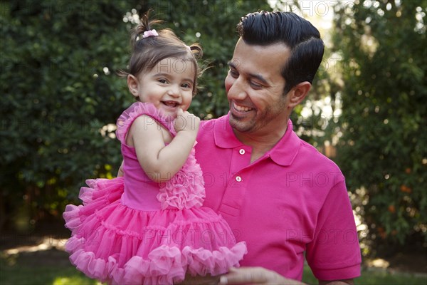 Father holding daughter in backyard