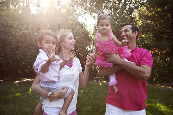 Parents holding children together in backyard