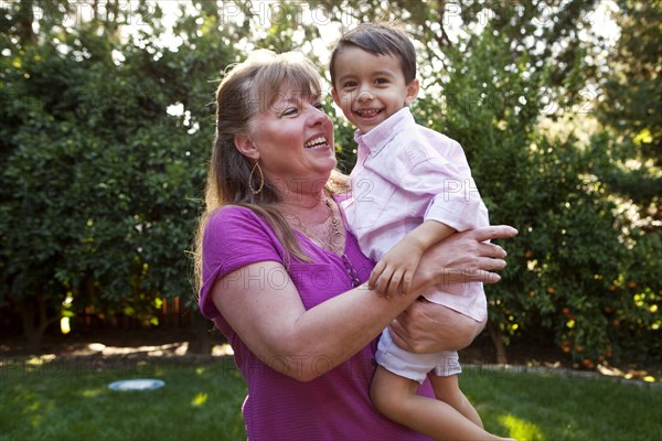 Grandmother holding grandson in backyard