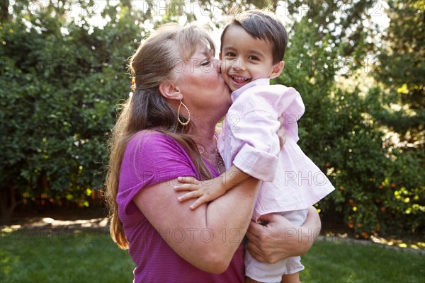 Grandmother kissing grandson in backyard