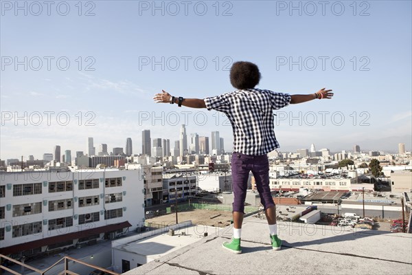African American man overlooking cityscape from urban rooftop