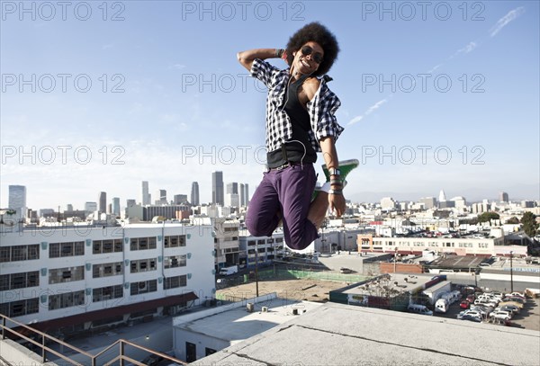 African American man jumping for joy on urban rooftop