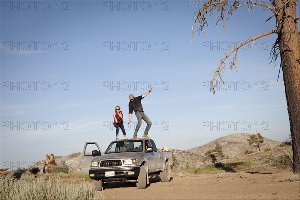 Caucasian couple standing on roof of pickup truck