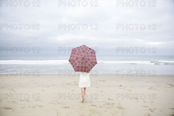 Woman standing with umbrella on beach