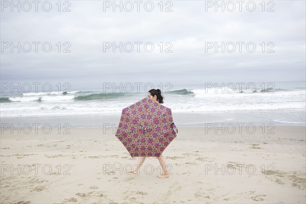 Woman walking with umbrella on beach