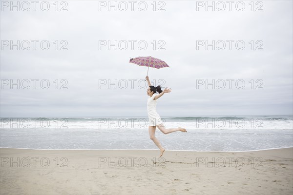 Woman playing with umbrella on beach