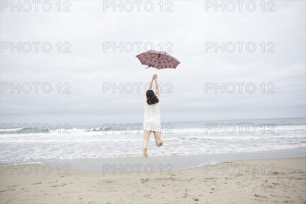 Woman playing with umbrella on beach