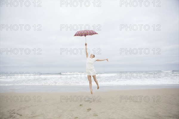 Woman playing with umbrella on beach