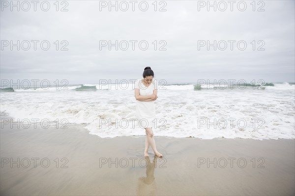 Woman standing near waves on beach