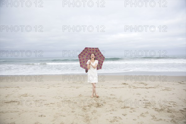 Woman laughing with umbrella on beach