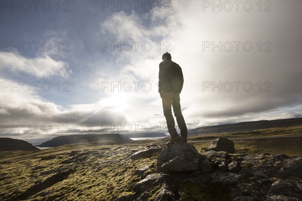 Caucasian man standing on rock in field