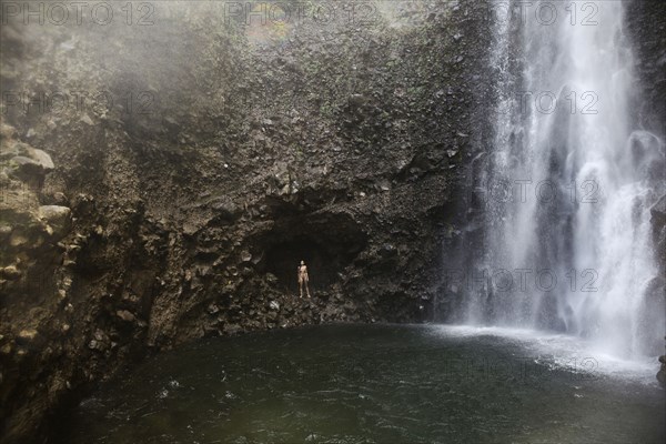 Mixed Race woman standing near waterfall pool