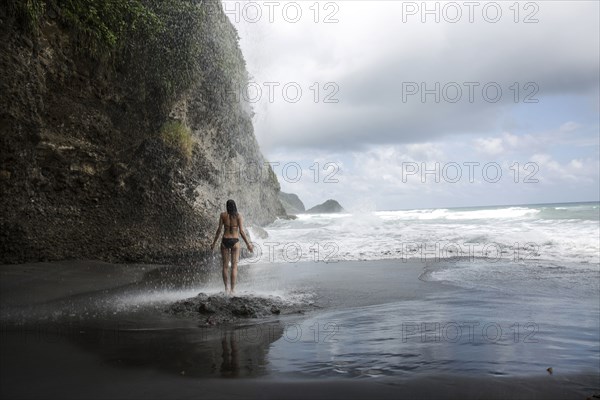 Mixed Race woman standing on rocks on ocean beach