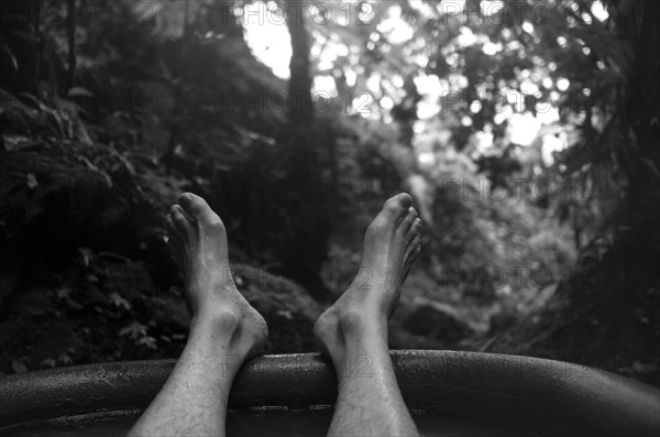 Feet of man soaking in tub outdoors