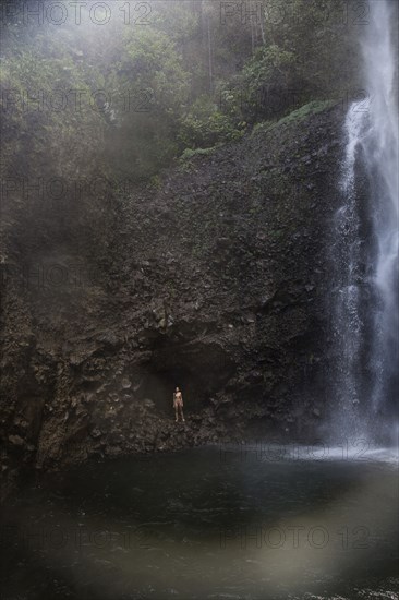 Mixed Race woman standing near waterfall pool