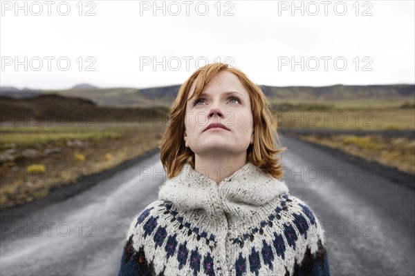 Caucasian woman wearing sweater in road looking up