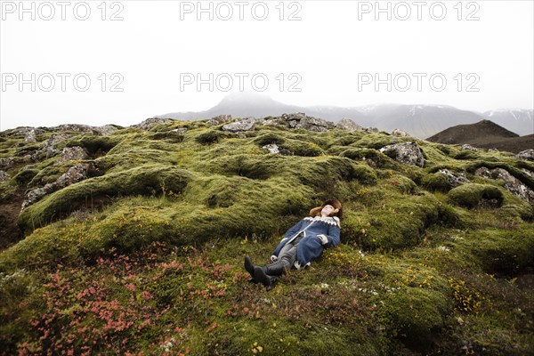 Caucasian woman laying on mossy rocks