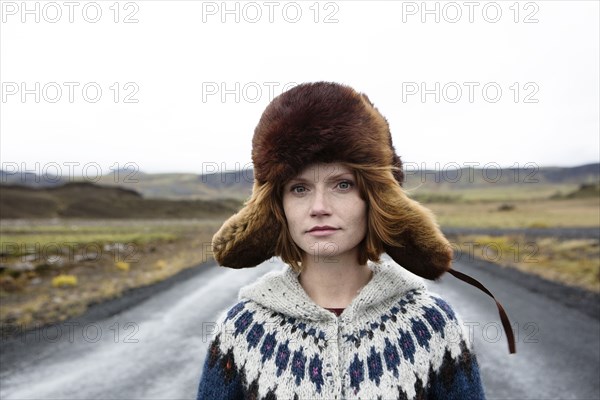 Caucasian woman wearing sweater and fur hat in middle of road