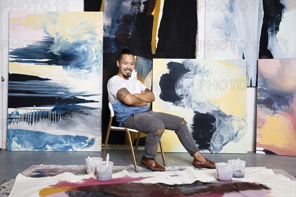 Pacific Islander painter admiring canvas on floor