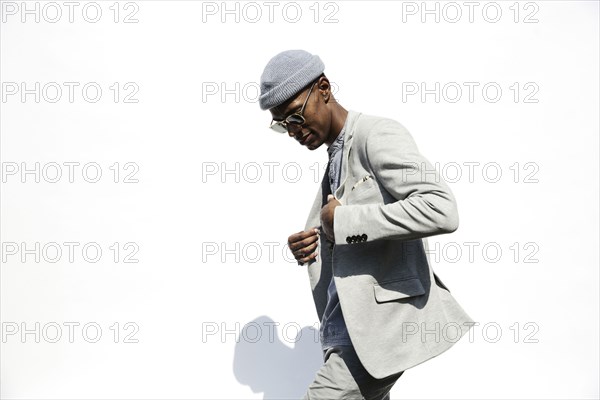 Black man wearing sunglasses adjusting jacket