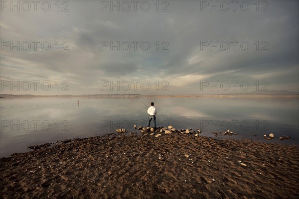 Distant man fishing on beach