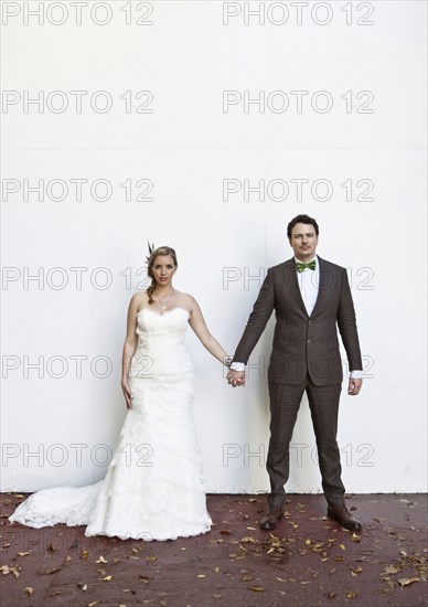 Serious Caucasian bride and groom holding hands