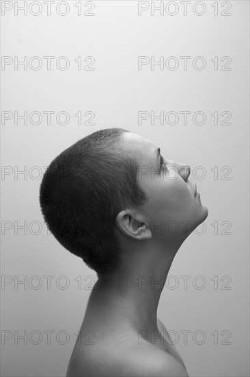 Profile of Caucasian woman with shaved-head looking up