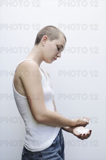 Serious Caucasian woman with shaved-head holding pills