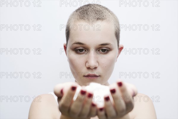 Serious Caucasian woman with shaved-head holding pills