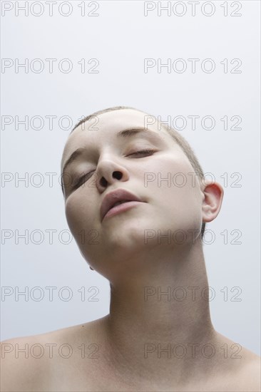 Caucasian woman with shaved-head and eyes closed