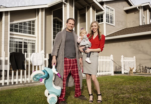 Caucasian couple posing on lawn with baby daughter