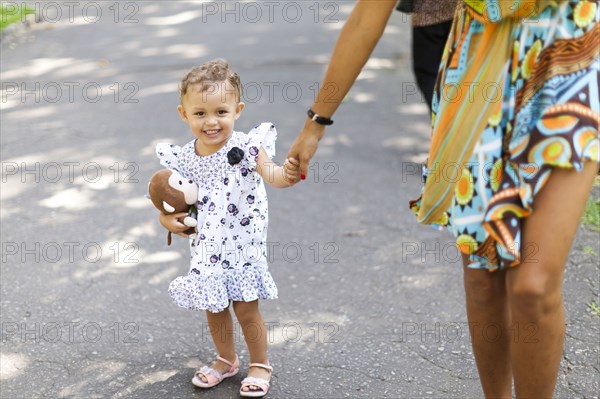 Mother and daughter walking on sidewalk