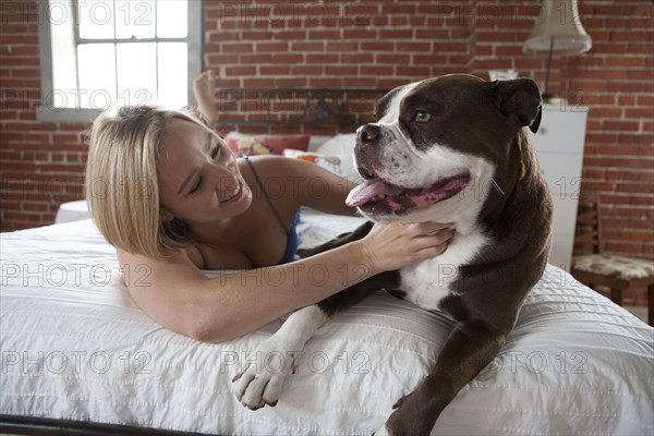 Caucasian woman petting dog on bed
