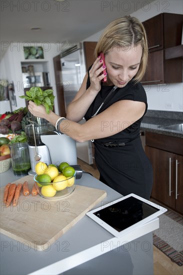 Caucasian businesswoman juicing in kitchen