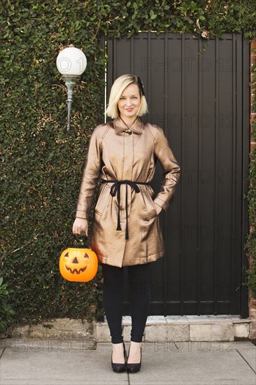 Caucasian woman carrying jack o' lantern bucket