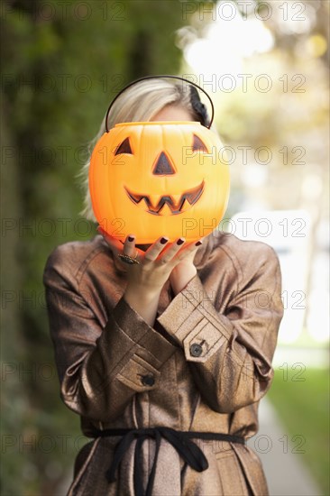 Caucasian woman holding jack o' lantern bucket