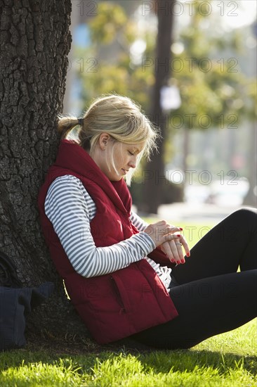 Caucasian woman leaning against tree in park