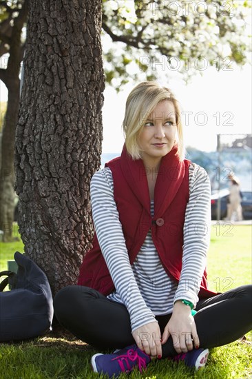 Caucasian woman sitting by tree in park
