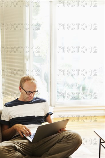 Caucasian man using laptop on sofa