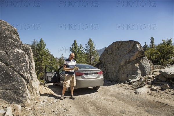 Man reading near car on dirt road