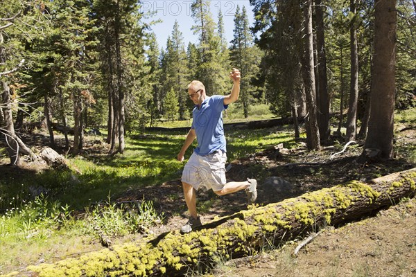 Man walking on log in forest