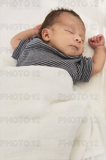 Mixed race baby sleeping on bed