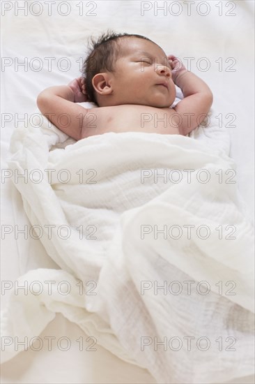 Mixed race baby sleeping on bed