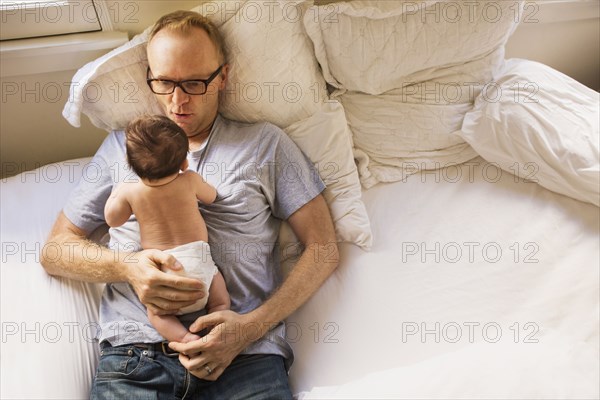 Father playing with baby on bed