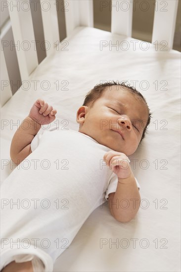 Mixed race baby sleeping in crib