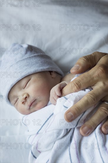 Close up of newborn baby holding finger of father