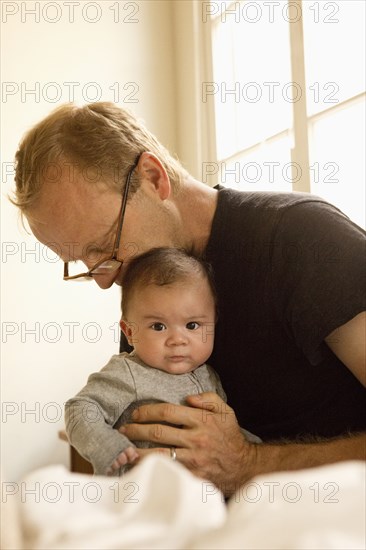 Father kissing baby boy on bed