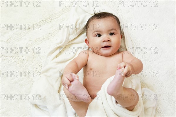 Mixed race baby playing with feet