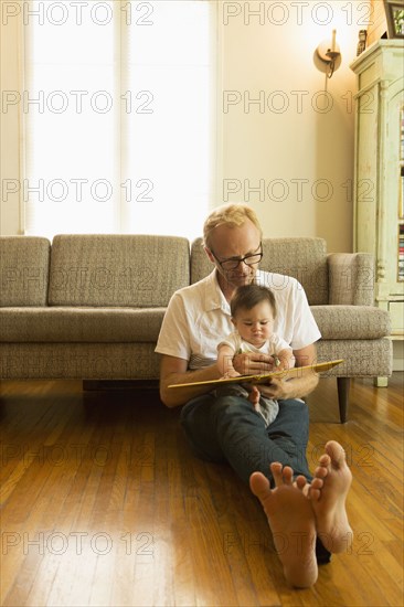 Father reading to son on living room floor